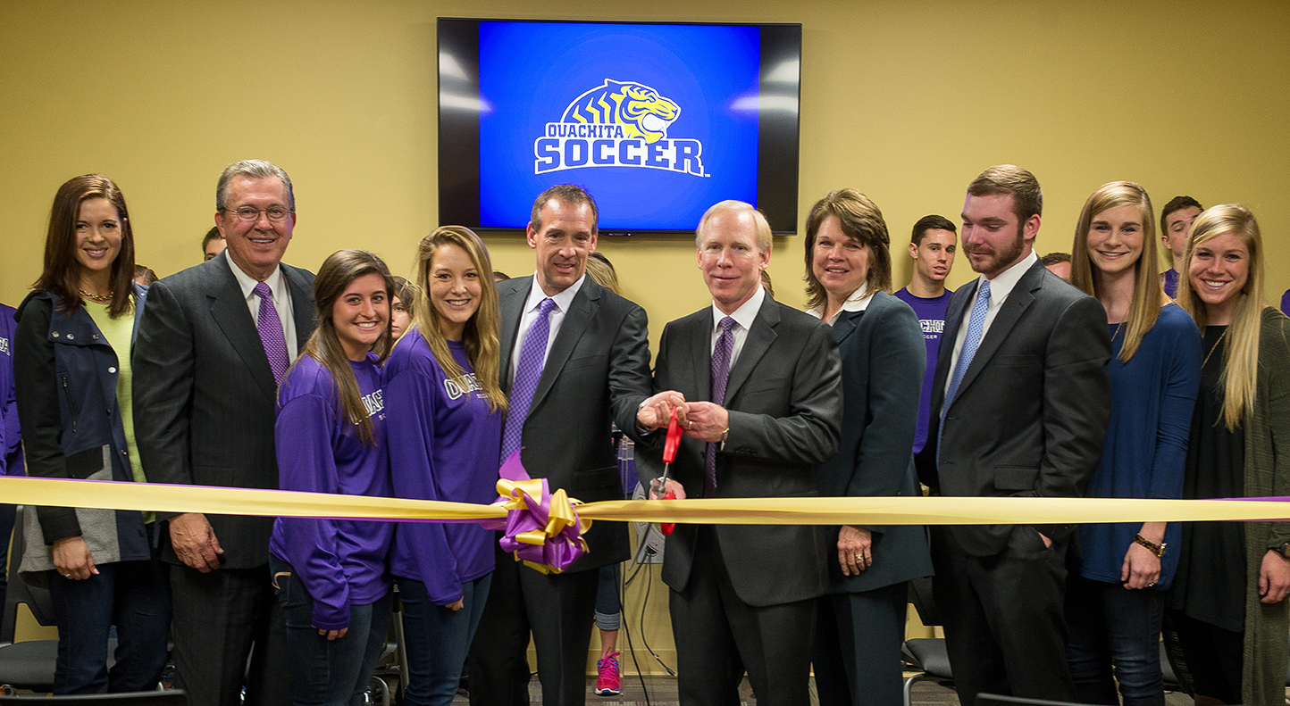 Ouachita President Rex Horne (second from left) with Greg Hatcher (fifth from left) and Gene Whisenhunt (sixth from left) complete the ceremonial ribbon-cutting for OBU’s Whisenhunt Fieldhouse alongside their family members and Ouachita soccer players.
