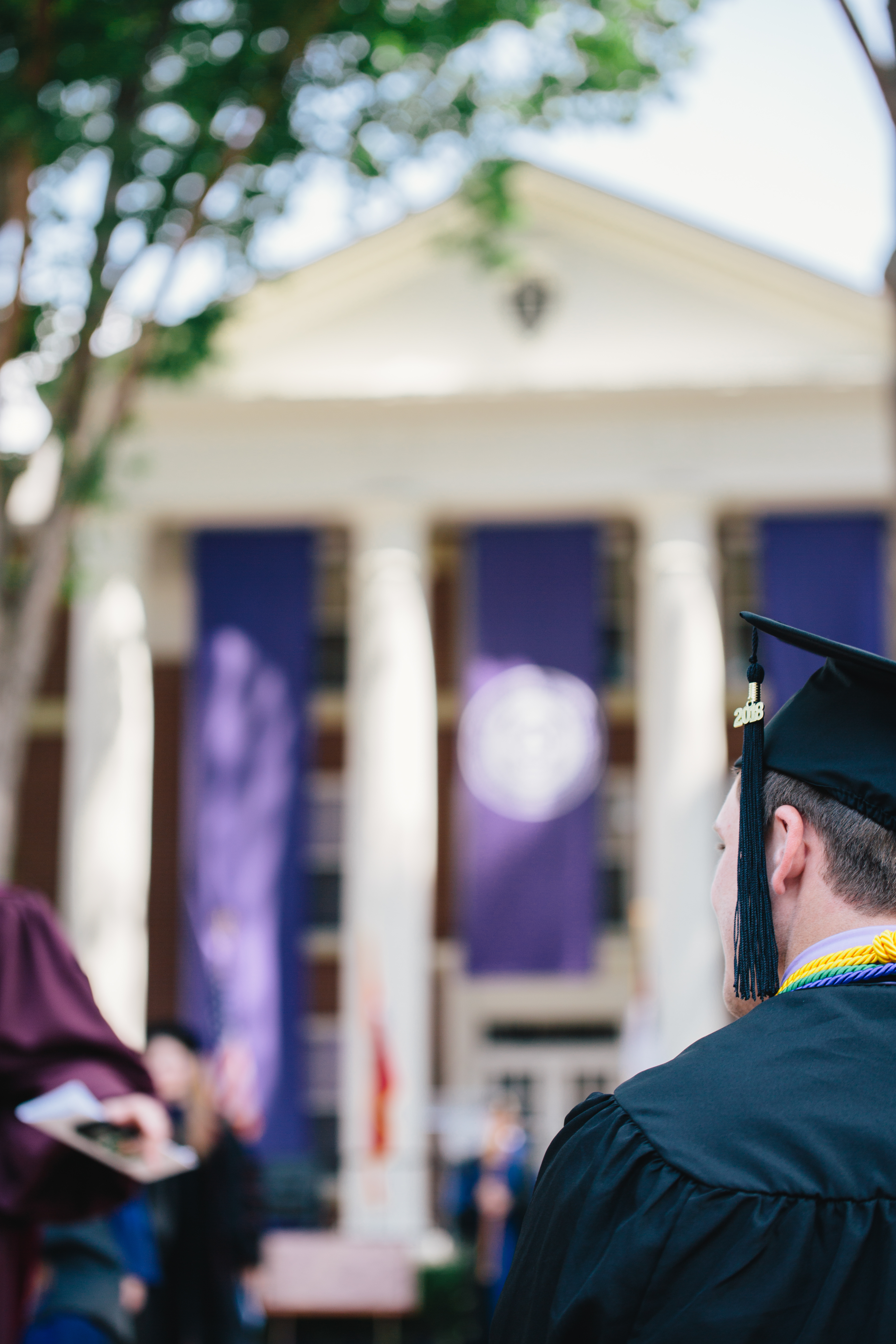 Student stands in front of Cone-Bottoms at Commencement