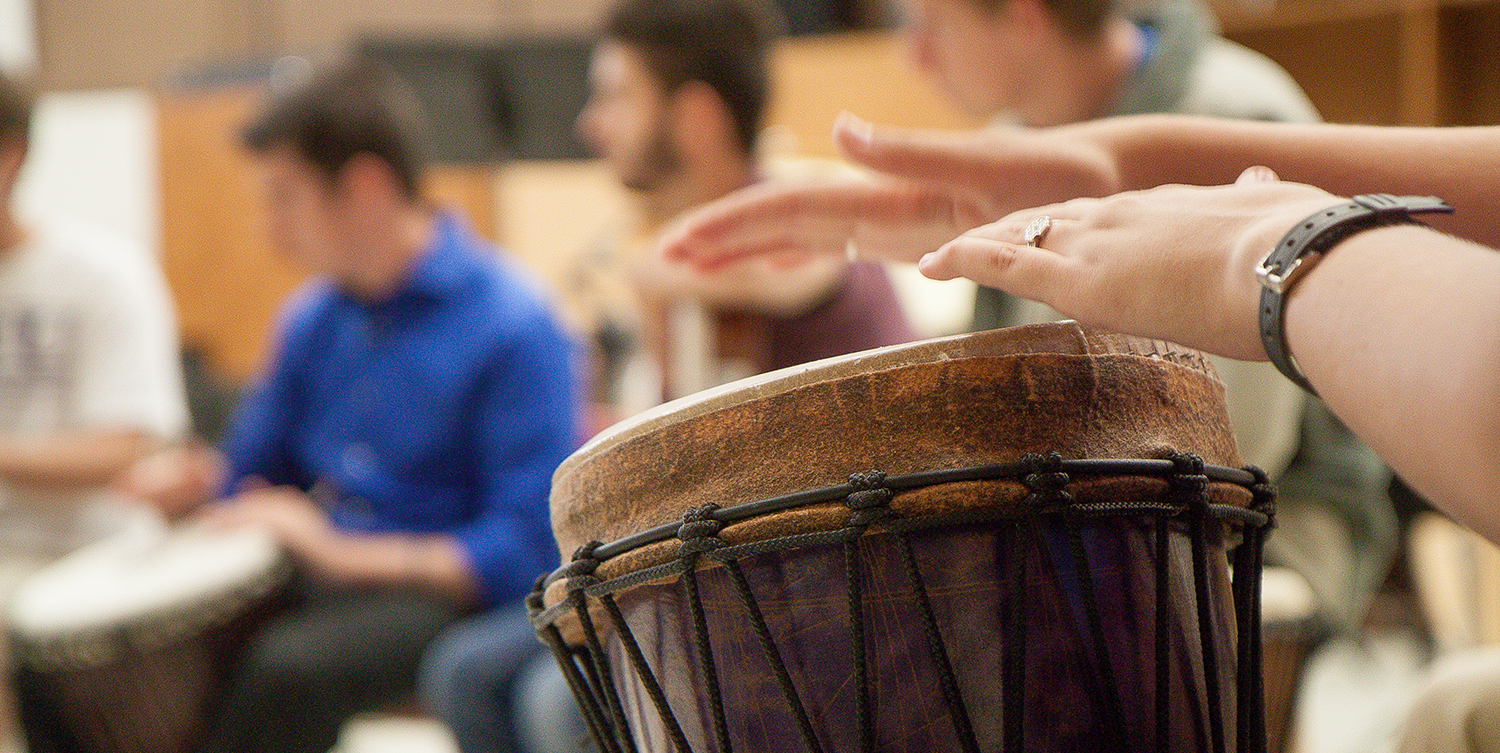 A student plays a bongo during percussion ensemble practice