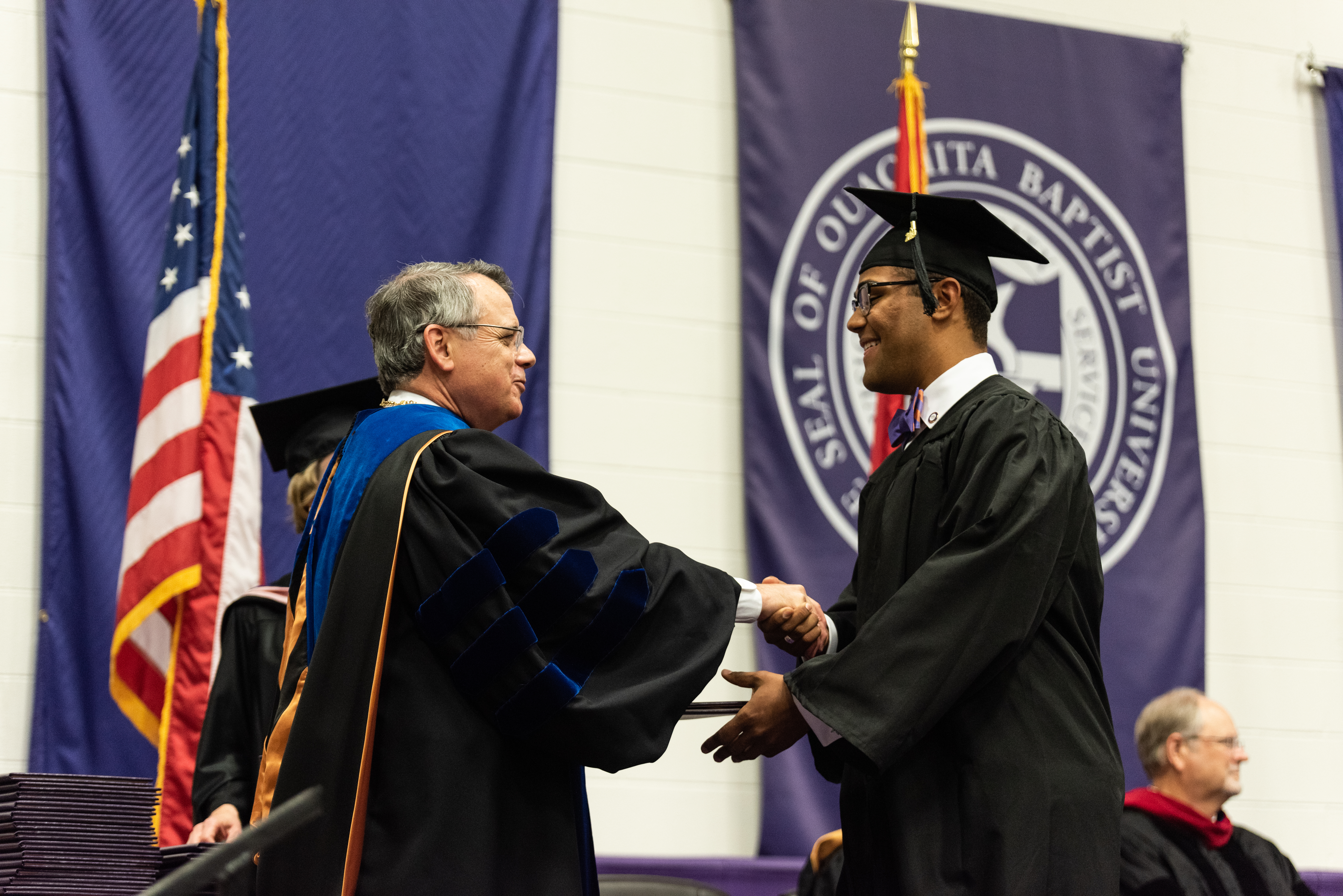President Ben Sells shakes student's hand at graduation