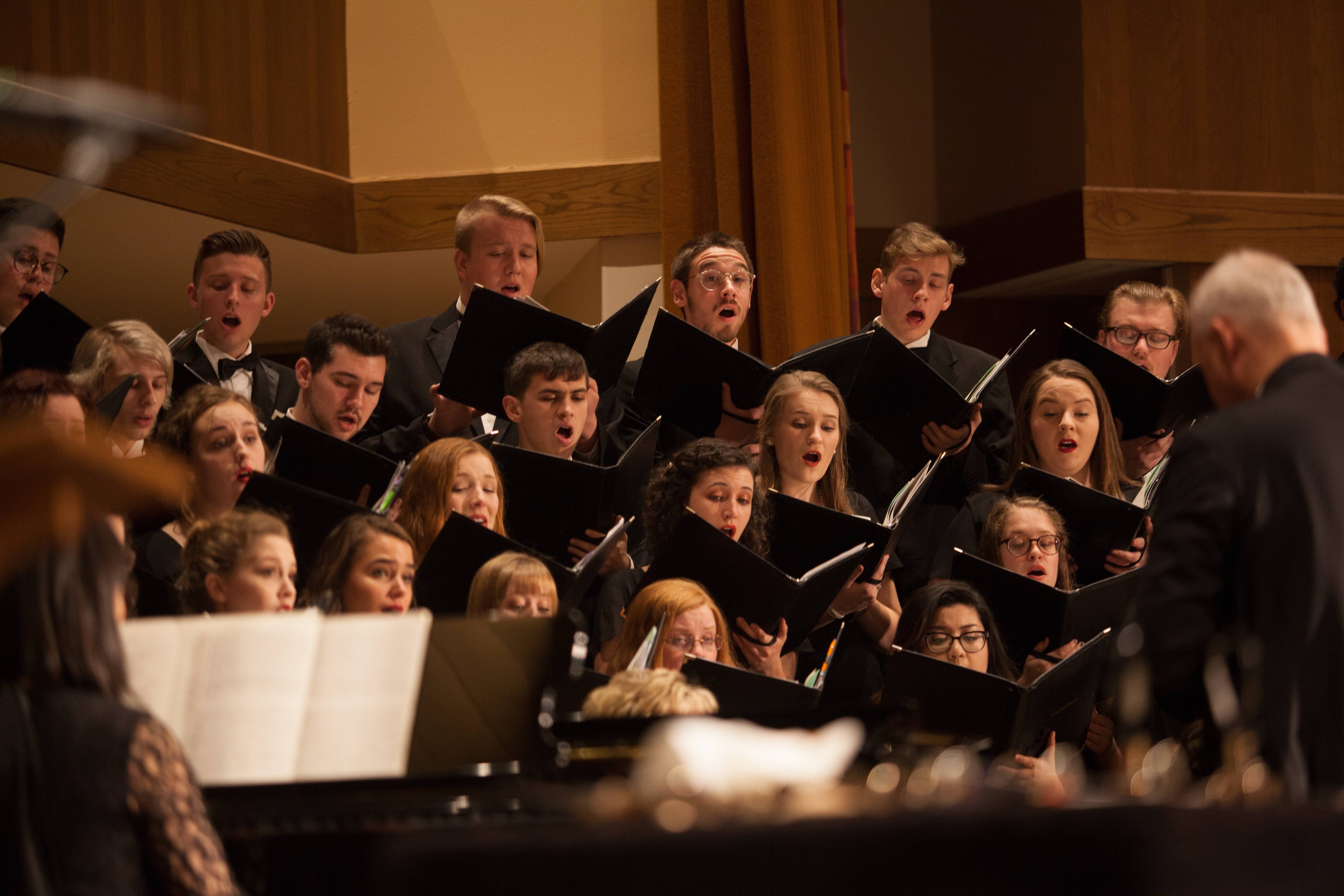 Choir members sing as conductor leads