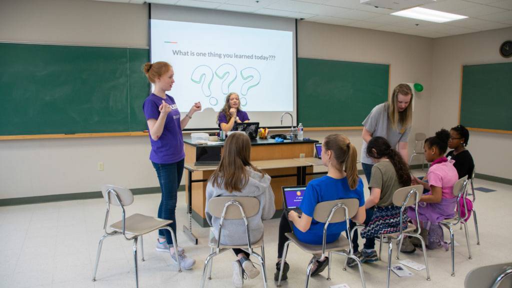 Students teaching elementary-age girls